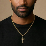 Man wearing a gold chain with a cross pendant on a beige background