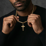 Man adjusting a gold chain with a crucifix pendant against a dark background